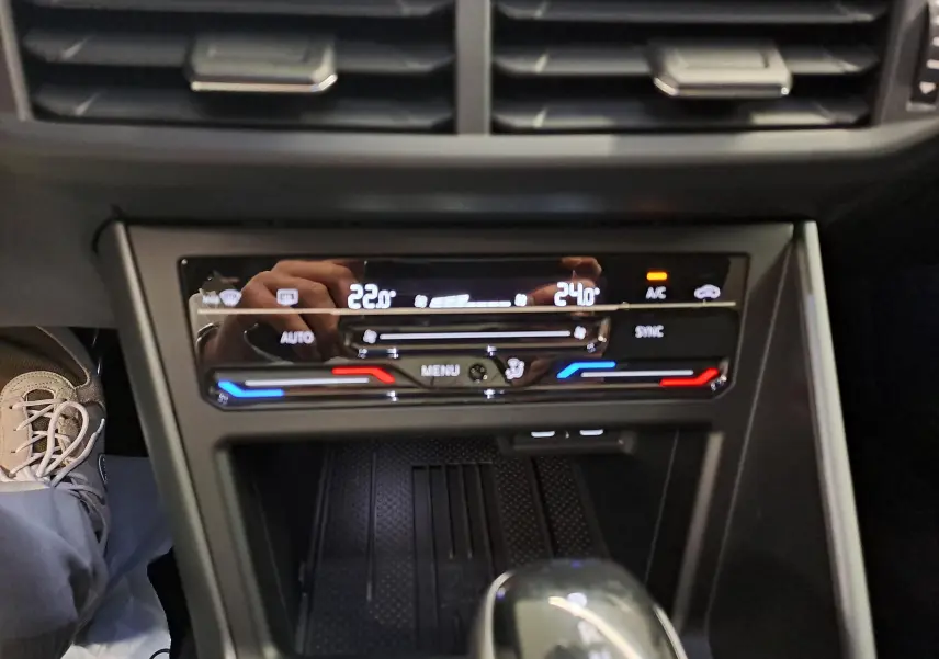 Gros plan sur la console centrale du Volkswagen Taigo 2025, affichant la climatisation bi-zone avec réglages numériques.