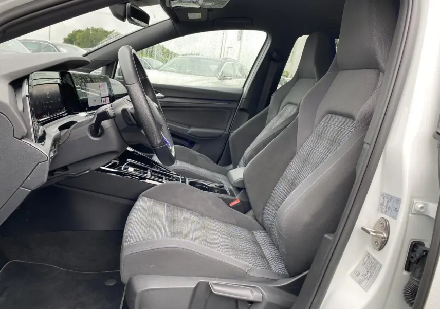 Intérieur côté conducteur de la Volkswagen Golf 1.4 eHybrid 2023, sièges tissu gris à motifs et volant sport cuir GTE.