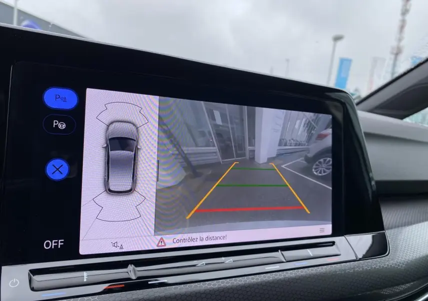 Écran de caméra de recul et assistance au stationnement dans l'habitacle d'une Volkswagen Golf blanche 2023.