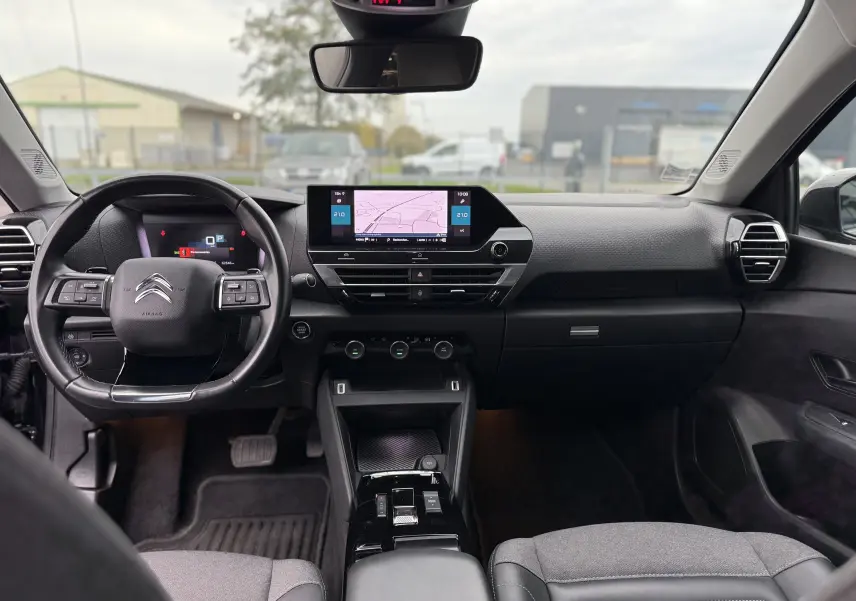 Vue intérieure avant du tableau de bord et volant noir du Citroën C4 1.5 BlueHDi 130 Shine avec écran tactile et commandes intégrées.