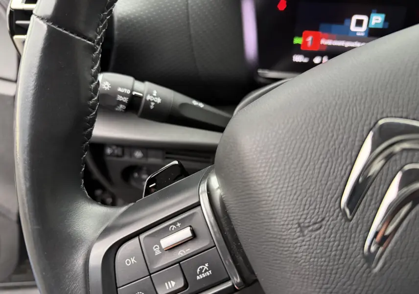 Gros plan sur le volant noir de la Citroën C4 2022, montrant les commandes de régulateur de vitesse et le logo Citroën.