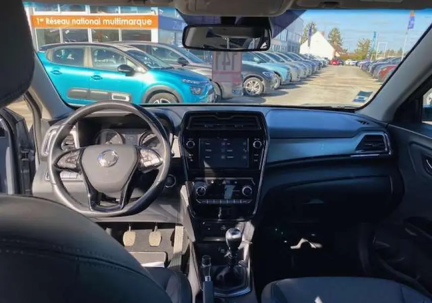 Vue intérieure avant du SsangYong Tivoli gris foncé 2021, tableau de bord moderne avec écran tactile et boîte manuelle.