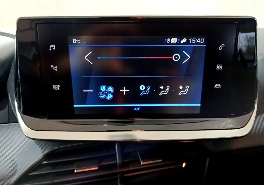 Écran tactile central de la Peugeot 208 blanc, affichant les réglages de climatisation intérieure.