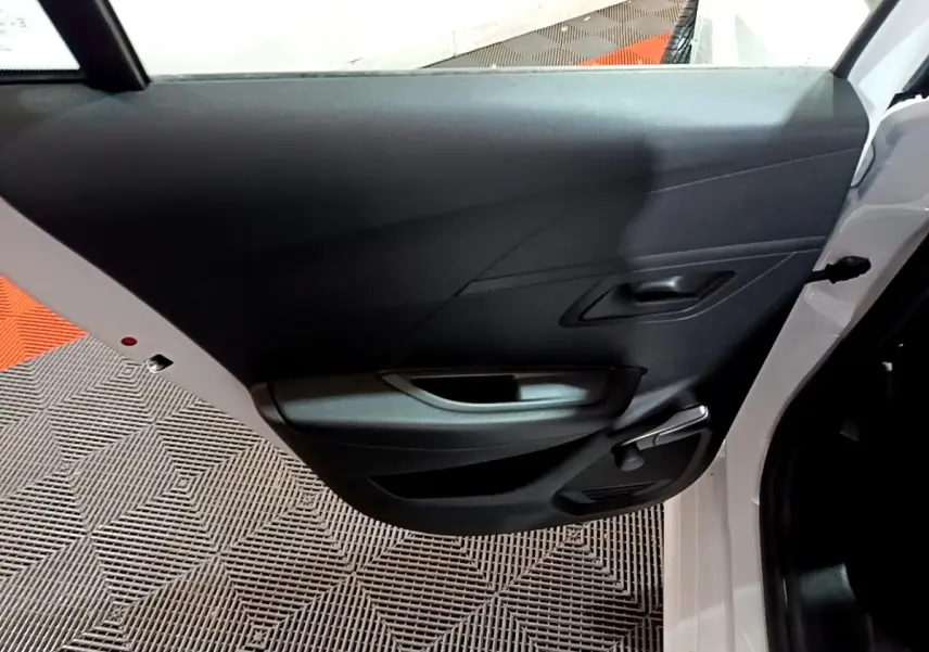 Vue intérieure de la porte arrière droite blanche d'une Peugeot 208 1.5 BlueHDi 100 S&S Premium avec poignée et manivelle de vitre.