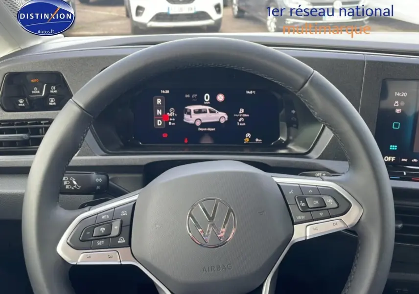 Vue intérieure centrée sur le volant cuir multifonction du Volkswagen Caddy blanc avec tableau de bord numérique.