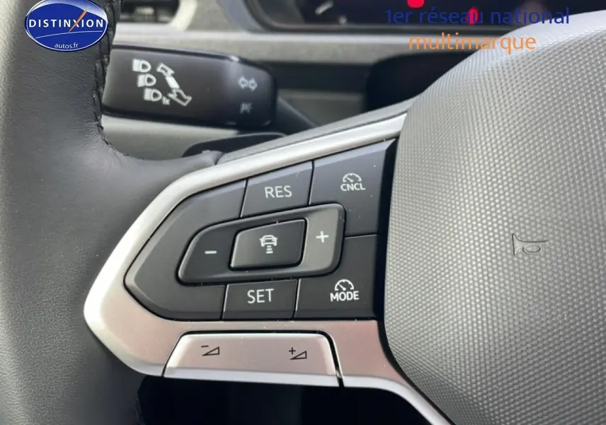 Gros plan sur les commandes du volant cuir multifonction du Volkswagen Caddy blanc, version 2025, côté gauche.