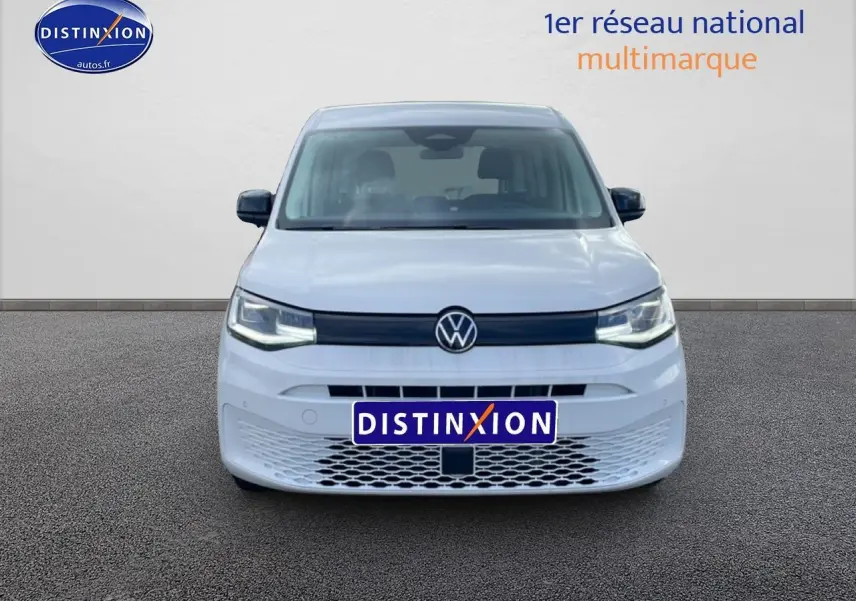 Vue de face du Volkswagen Caddy blanc 2025 avec calandre noire et logo VW centré, sur fond neutre.