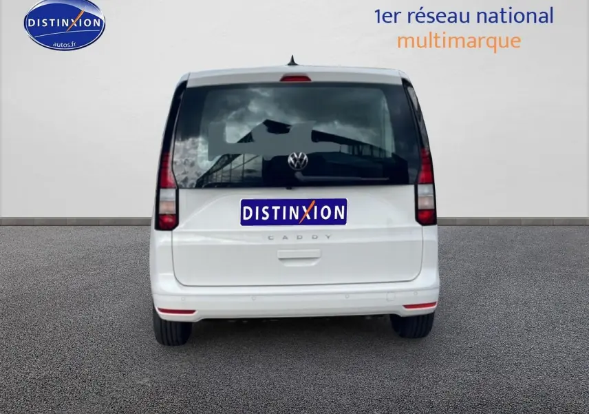 Vue arrière d'un Volkswagen Caddy blanc 2025 avec vitres teintées et feux verticaux rouges.