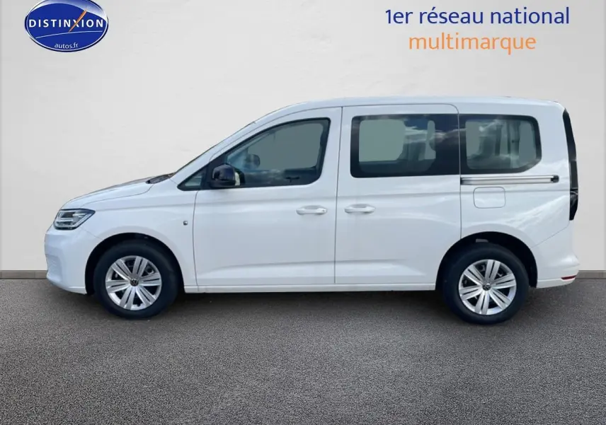 Profil droit d'un Volkswagen Caddy blanc 2025, avec barres de toit et jantes alliage visibles.