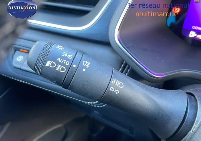 Gros plan sur la commande des phares et clignotants dans l’habitacle du Renault Symbioz bleu Iron Metal, tableau de bord partiellement visible.
