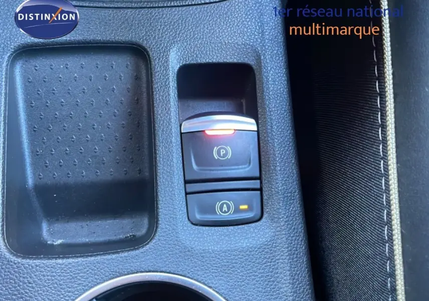 Gros plan sur la console centrale noire du Renault Symbioz 2025, avec boutons de frein à main et arrêt automatique éclairés.