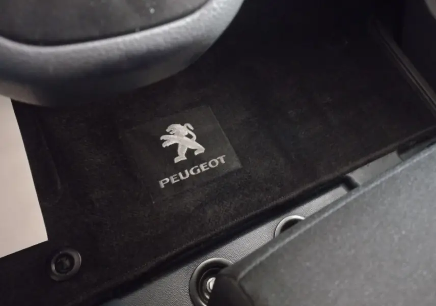 Vue rapprochée du tapis de sol noir avec logo Peugeot à l'avant gauche du Peugeot Traveller gris clair 2021.