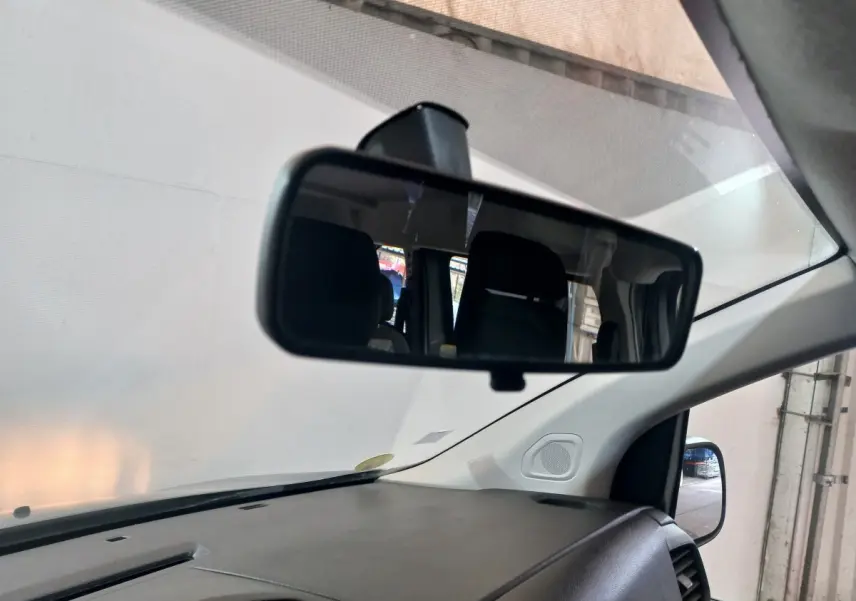 Vue intérieure du rétroviseur central du Peugeot Traveller gris clair, montrant partiellement les sièges arrière et le tableau de bord.