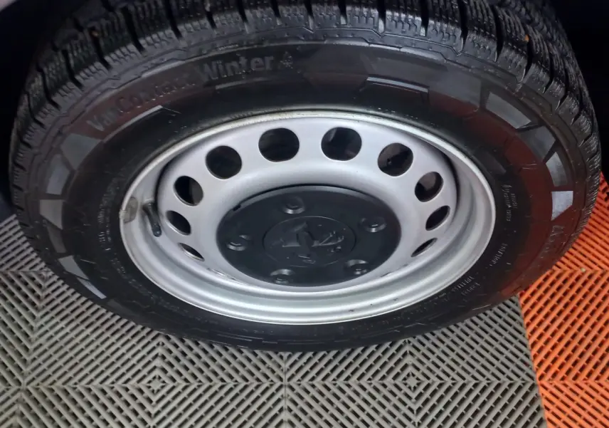 Gros plan sur la roue avant avec jante acier grise et pneu hiver du Peugeot Traveller gris clair 2021.