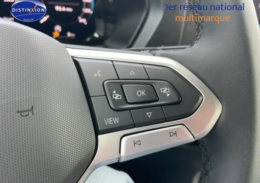 Gros plan sur les commandes multifonctions du volant cuir du Volkswagen Caddy 2025, version 2.0 TDI gris indien.