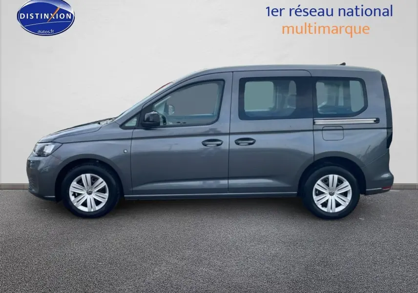 Vue de profil côté gauche d'un Volkswagen Caddy gris indien 2025 avec vitres arrière teintées et jantes alliage.