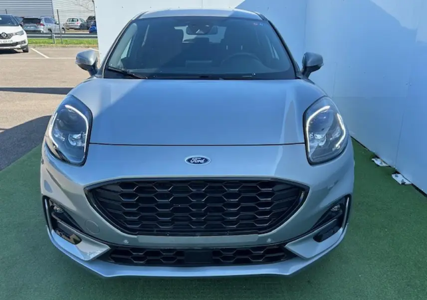 Vue avant d'un Ford Puma gris Magnetic 2023 avec calandre noire hexagonale et phares LED allumés.