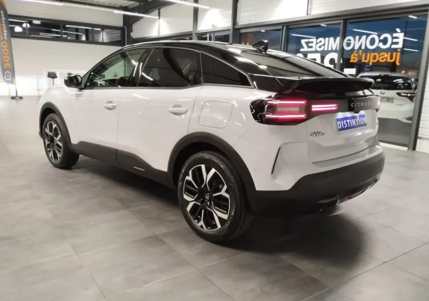 Vue 3/4 arrière droite d'une Citroën C4 blanche Okenite avec toit noir et jantes alliage 18'' dans un showroom.