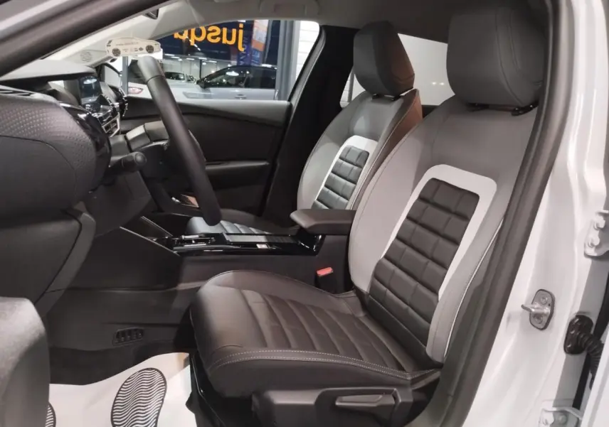 Vue intérieure côté conducteur de la Citroën C4 2025 blanche, sièges Advanced Comfort bicolores noir et gris.