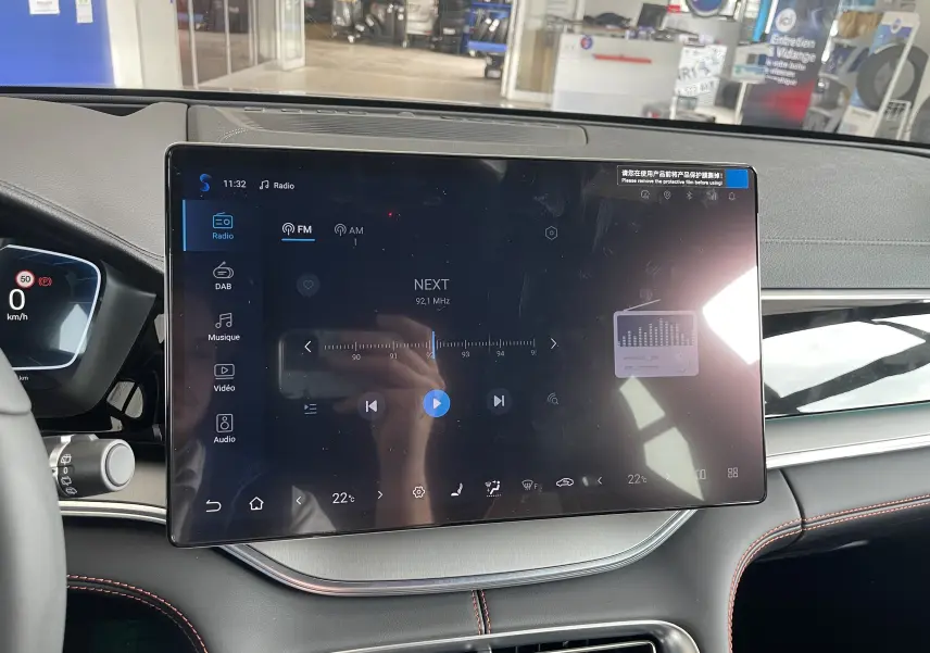 Vue rapprochée de l'écran tactile central du tableau de bord du BYD SEAL U 2025, avec affichage radio et détails intérieurs noirs et gris.