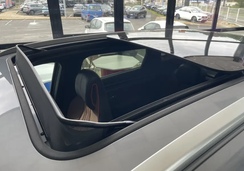 Vue en plongée du toit ouvrant panoramique ouvert d'un BYD SEAL U gris Time Grey, avec sièges avant visibles à l'intérieur.