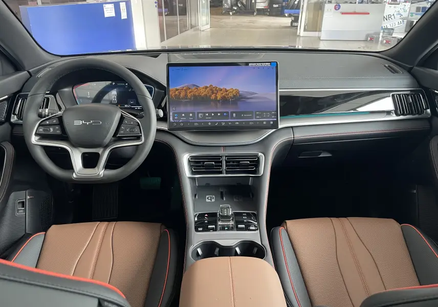 Vue intérieure avant du BYD SEAL U 2025 avec sièges en similicuir marron, grand écran tactile central et volant multifonction noir.