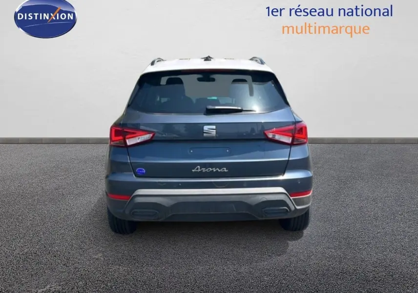 Vue arrière d'un SEAT Arona gris Magnetic Metal avec toit blanc, feux arrière allumés sur fond neutre.