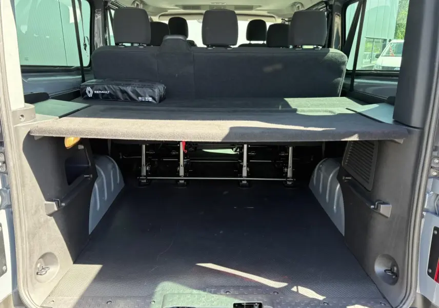 Vue arrière ouverte du Renault Trafic Fourgon Urban Grey montrant le coffre spacieux et la banquette arrière noire.