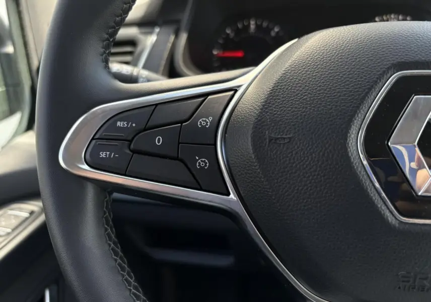 Gros plan sur le volant noir du Renault Trafic Fourgon 2024, mettant en valeur les commandes de régulateur de vitesse.
