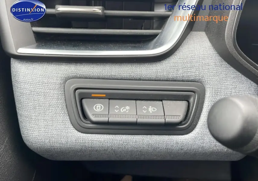 Boutons de réglage des feux et verrouillage sur tableau de bord gris clair de Renault Clio V blanche, vue intérieure côté conducteur.