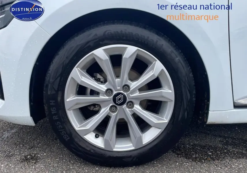 Gros plan sur la roue avant droite avec jante argentée de la Renault Clio V blanche.