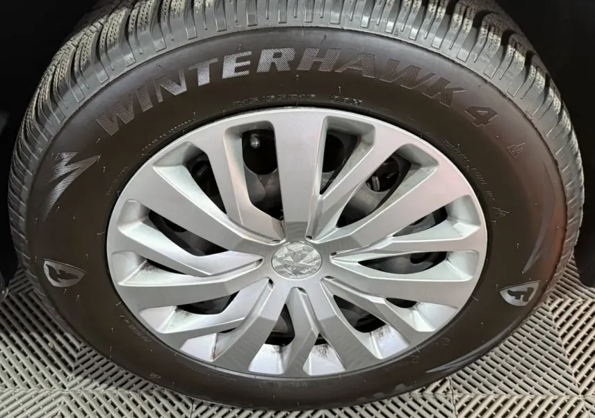 Gros plan sur la roue avant droite du Peugeot Rifter blanc, mettant en valeur la jante argentée et le pneu hiver Winterhawk 4.