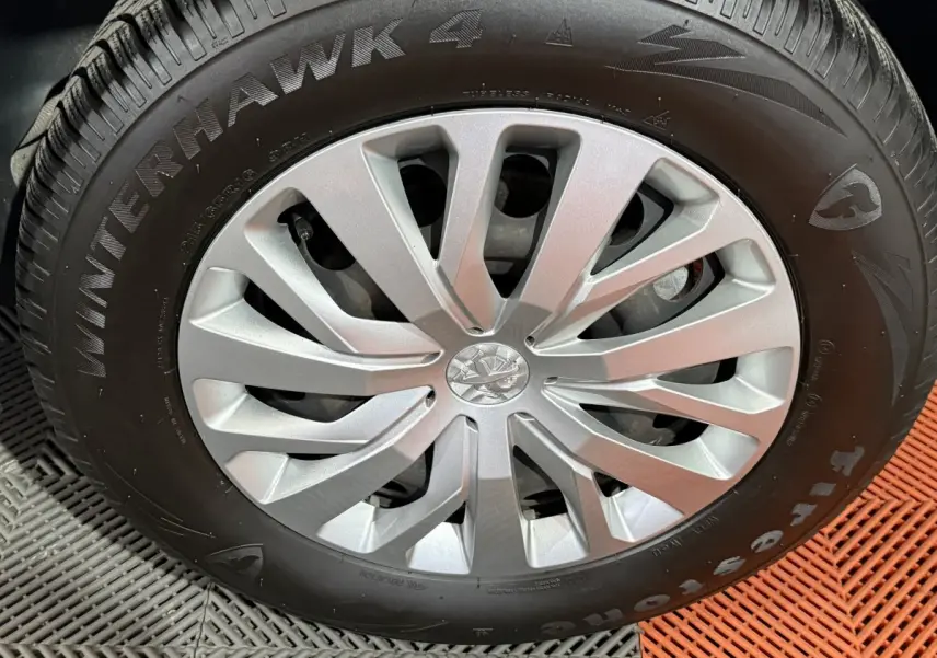 Gros plan sur la roue avant avec jante argentée et pneu Firestone Winterhawk 4 sur Peugeot Rifter blanc.