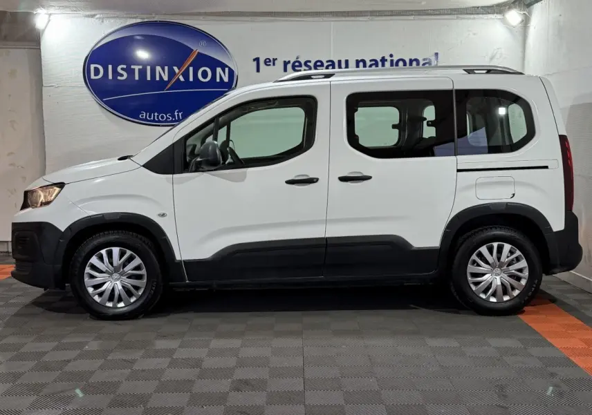 Vue de profil côté gauche d'un Peugeot Rifter blanc 2019 avec rails de toit chromés et jantes argentées.