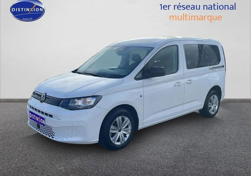 Volkswagen Caddy blanc vue 3/4 avant droit avec phares halogènes et jantes alliage simples.