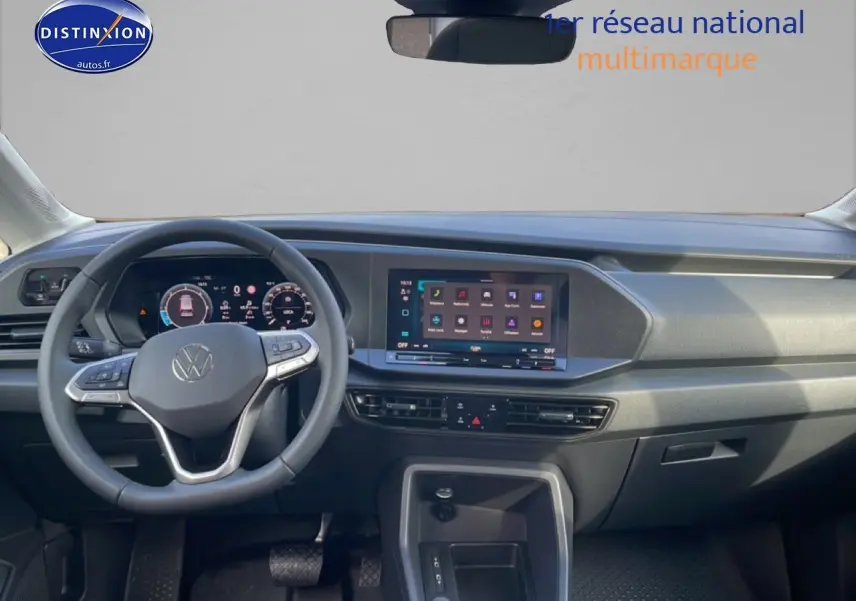 Vue intérieure frontale du tableau de bord du Volkswagen Caddy 2025 avec écran tactile et volant multifonction cuir.