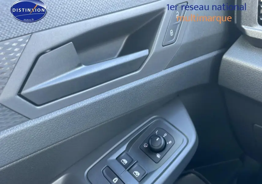 Gros plan sur la porte avant gauche du Volkswagen Caddy blanc, montrant les commandes des vitres et rétroviseurs.