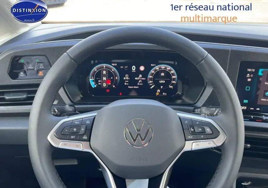 Vue intérieure centrée sur le volant cuir multifonction et l'instrumentation numérique du Volkswagen Caddy blanc 2025.