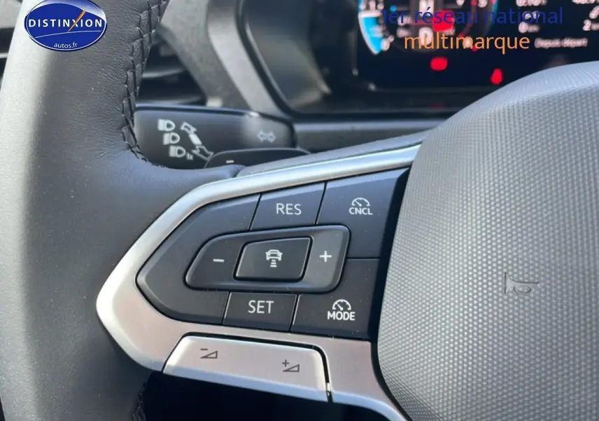 Gros plan sur le volant cuir multifonction du Volkswagen Caddy blanc, avec commandes de régulateur adaptatif visibles.