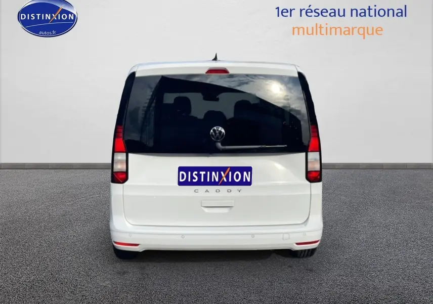 Vue arrière d'un Volkswagen Caddy blanc 2025 avec vitres arrière teintées et feux verticaux rouges.