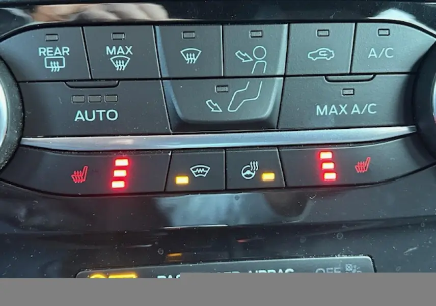 Gros plan sur les commandes de climatisation et sièges chauffants du Ford Puma gris Solar, avec voyants rouges allumés.