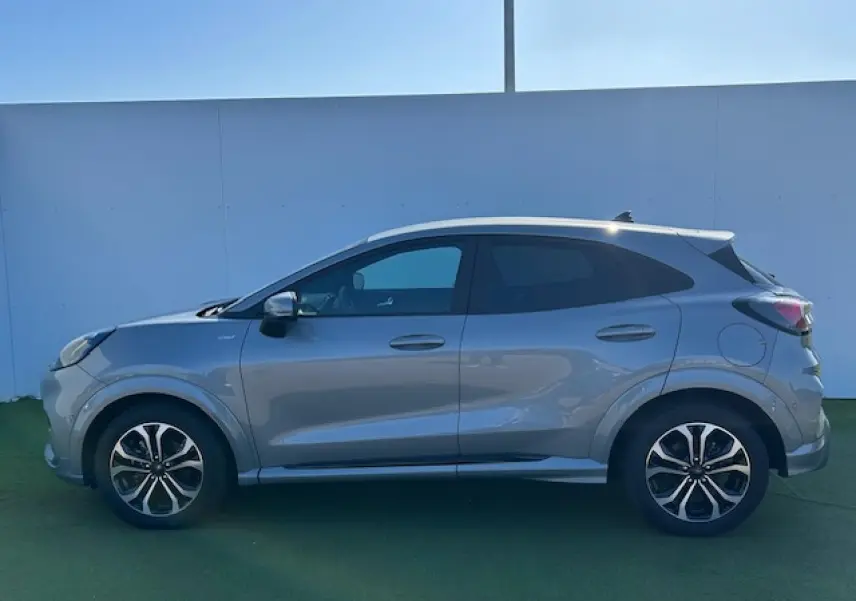 Profil côté gauche du Ford Puma gris Solar 2023 avec jantes alliage et vitres arrière surteintées.