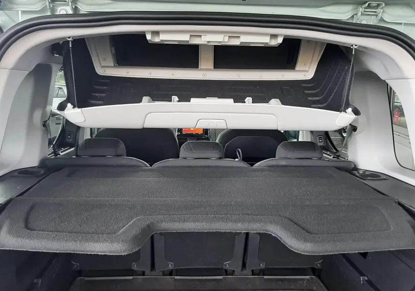 Vue arrière du coffre ouvert d'un Citroën Berlingo vert 2019, montrant la tablette cache-bagages et l'intérieur sombre.