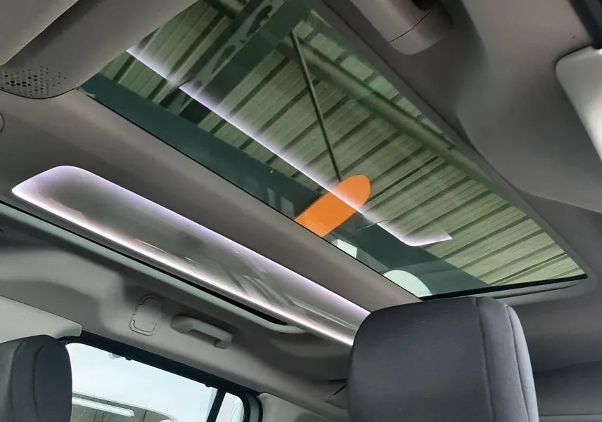 Vue intérieure du toit panoramique et des sièges avant gris foncé du Citroën Berlingo vert 2019.