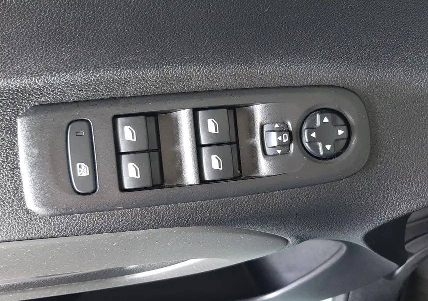 Gros plan sur les commandes de lève-vitres et réglage des rétroviseurs côté conducteur d'un Citroën Berlingo vert 2019.