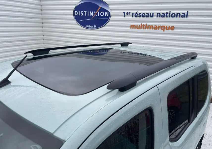 Toit panoramique et barres de toit noires sur le dessus d'un Citroën Berlingo vert vue en léger plongée arrière droite.