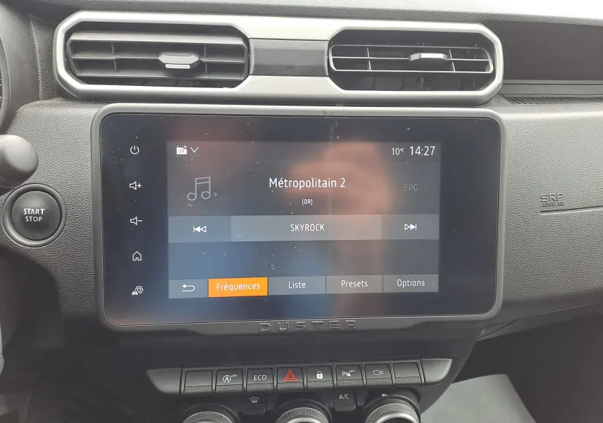 Vue rapprochée de l’écran tactile central et des commandes du tableau de bord du Dacia Duster gris urbain 2024.