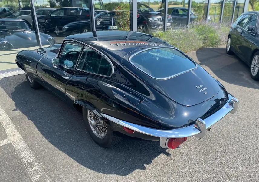 Vue 3/4 arrière droite d'une Jaguar S-Type noire de 1970 avec jantes à rayons et pare-chocs chromés distinctifs.