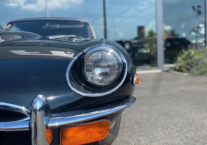 Vue rapprochée avant droite de la Jaguar S-Type noire 1970, avec phare rond et clignotant orange visible.