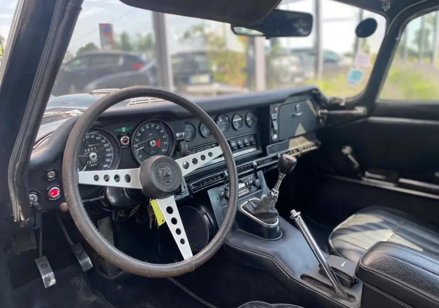 Intérieur noir vu côté conducteur d'une Jaguar S-Type Type E Coupé 4.2 Série 2 de 1970 avec volant trois branches et levier de vitesse manuel.